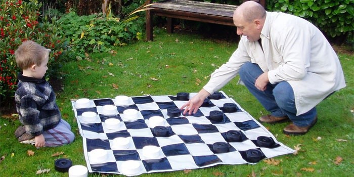 Отец обучает малыша игре в шашки