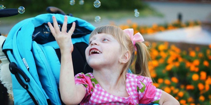 Девочка в коляске играет с мыльными пузырями