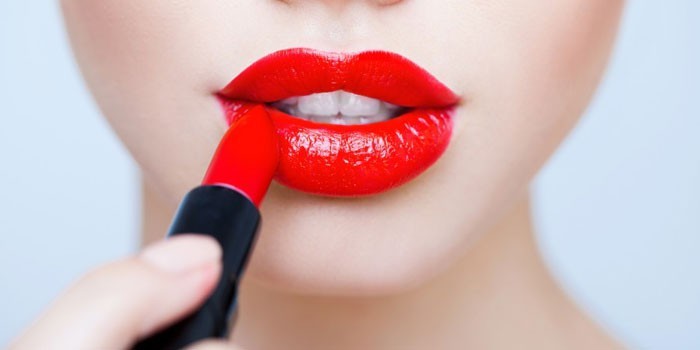 Девушка красит губы красной помадой