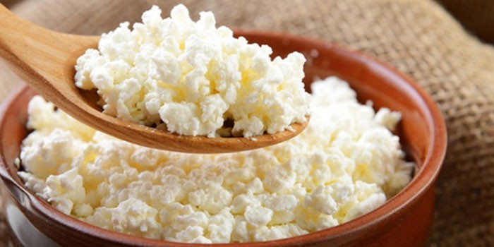 Творог в тарелке и деревянной ложке
