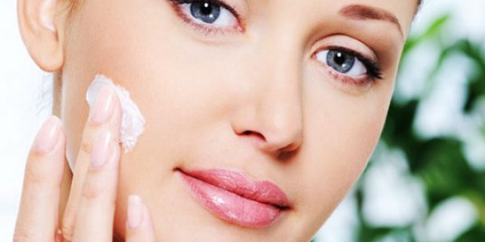 Девушка наносит крем на лицо