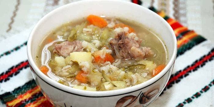 Рассольник с мясом, перловкой и солеными огурцами в тарелке