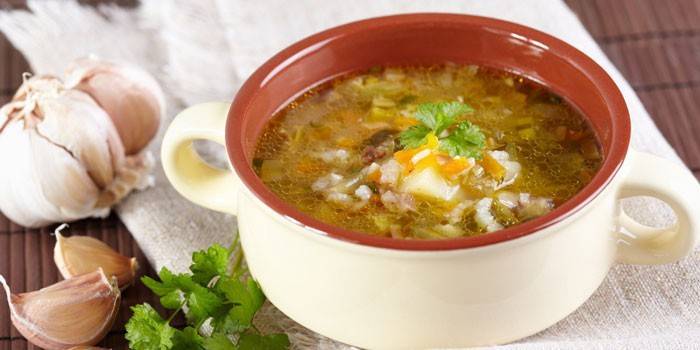 Рассольник с рисом и солеными огурцами в тарелке
