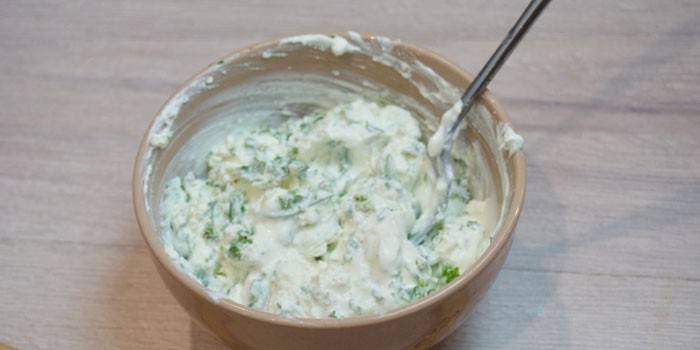 Творог с чесноком и зеленью в тарелке