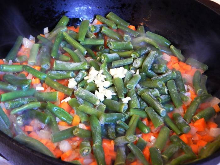 Добавление фасоли и чеснока к моркови и луку