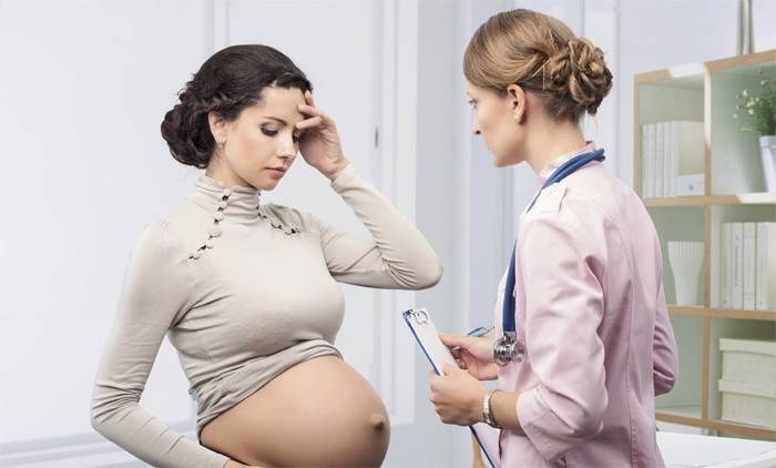 Беременная девушка говорит врачу о выделениях