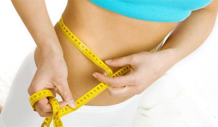Женщина измеряет объем талии после похудения
