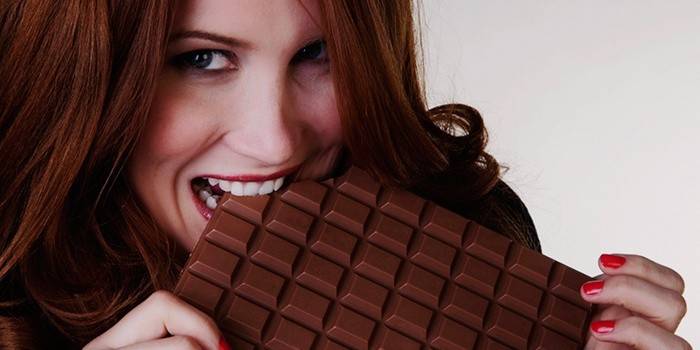 Девушка ест большую шоколадку