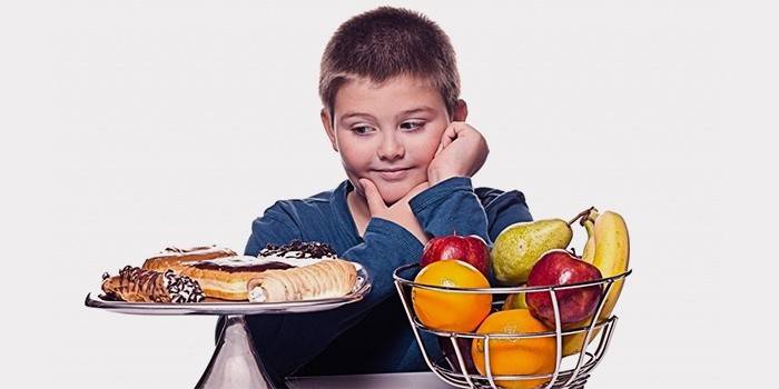 Мальчик-подросток выбирает между сладостями и фруктами