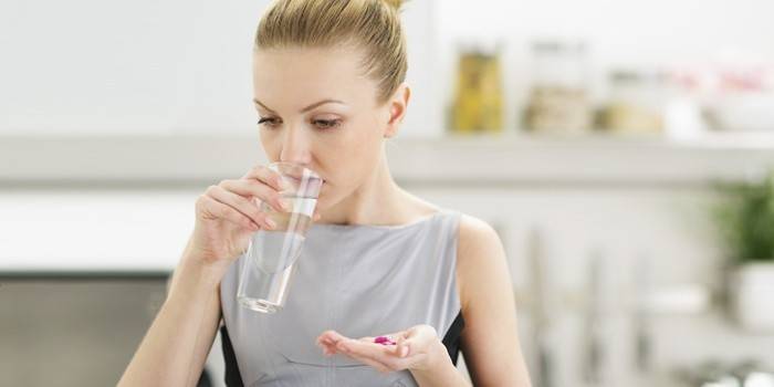 Женщина принимает таблетки, которые могут быть причиной целлюлита