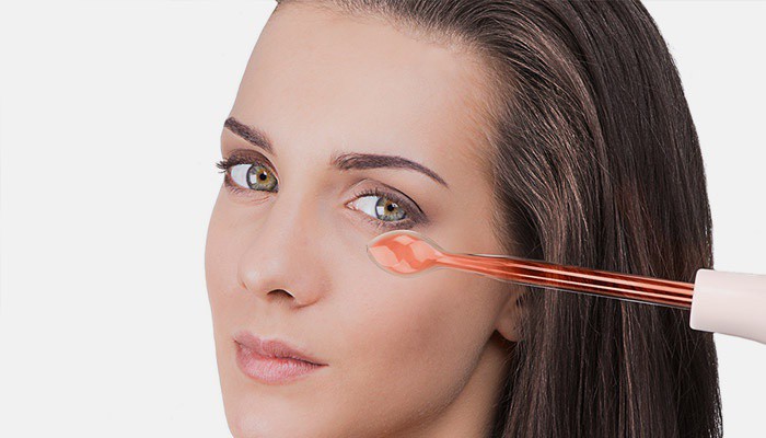 Девушка пользуется дарсонвалем для кожи лица