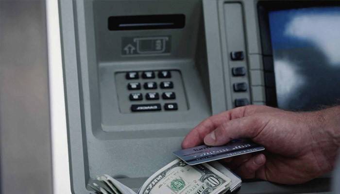 Мужчина получает деньги в банкомате