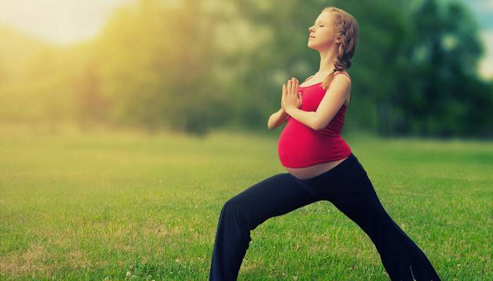 Беременная девушка занимается упражнениями на свежем воздухе