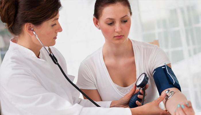 Доктор измеряет пульс и давление девушке с учащенным сердцебиением