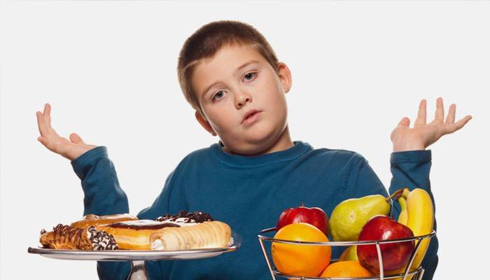 Мальчик выбирает между сладостями и фруктами