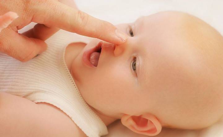 Женщина чистит нос новорожденному