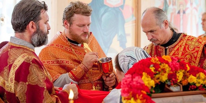 Священники причащают прихожанку