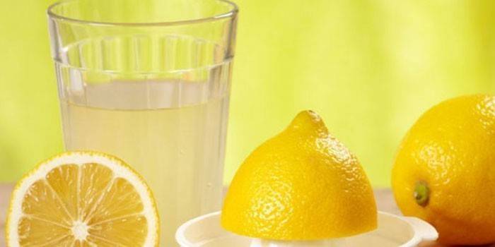 Лимонный сок в стакане и лимоны