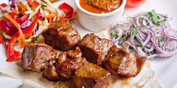 Куски свиного мяса с салатами и соусом