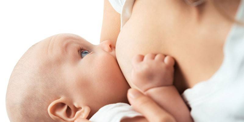 Женщина кормит младенца грудью