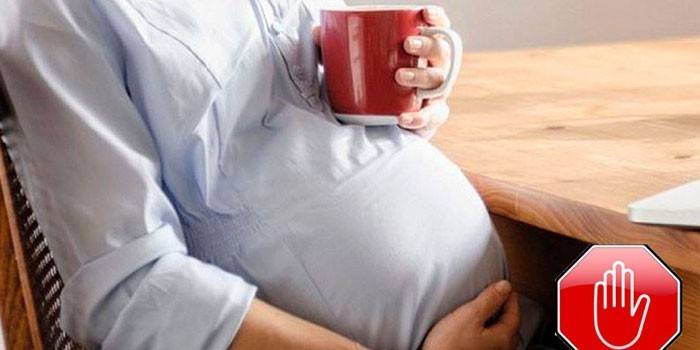 Беременная женщина держит чашку 