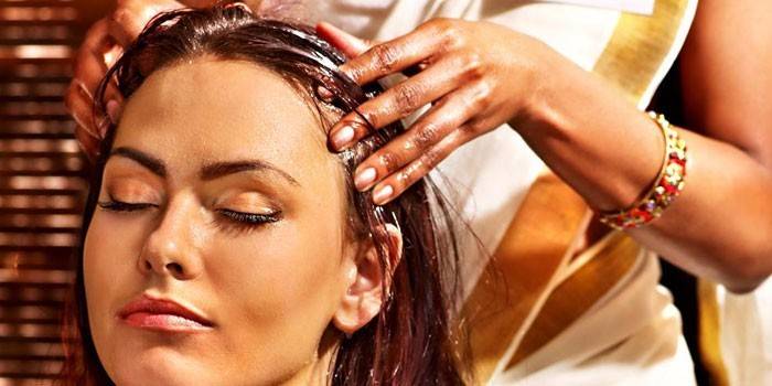 Женщине делают масляный массаж головы