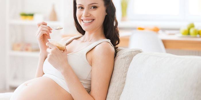 Беременная девушка сидит на диване