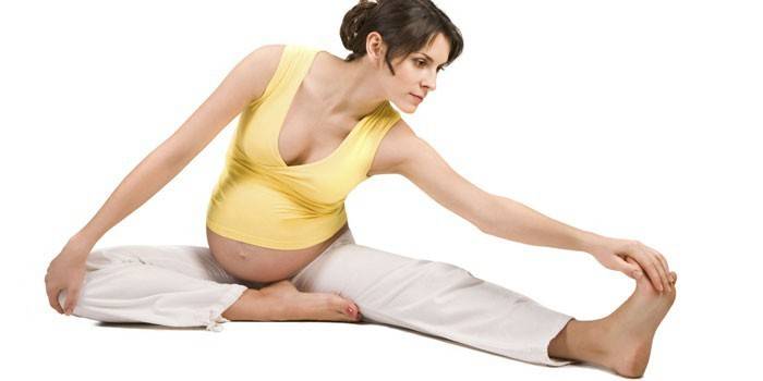 Беременная девушка делает упражнения на растяжку