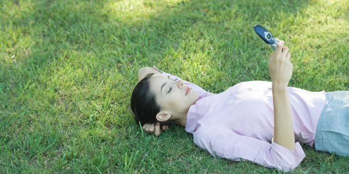 Девушка лежит на траве с телефоном