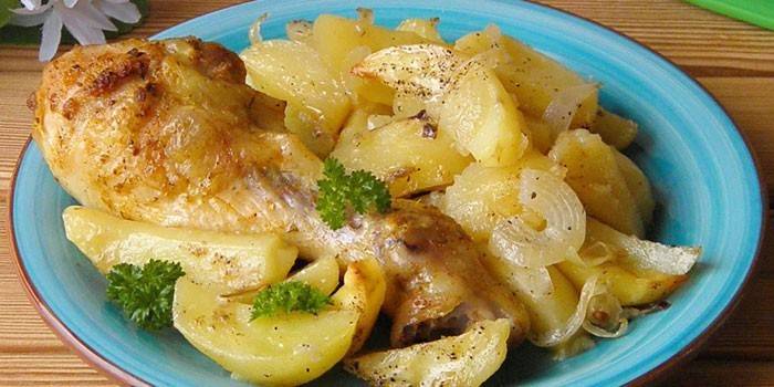 Куриная голень с картофелем и луком на тарелке 