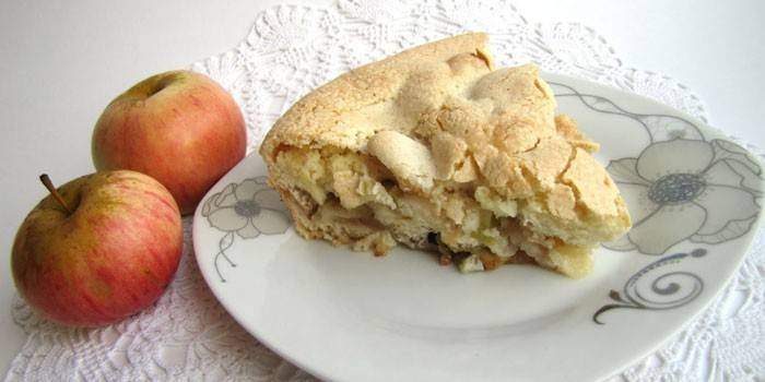 Кусочек яблочного пирога на тарелке и яблоки