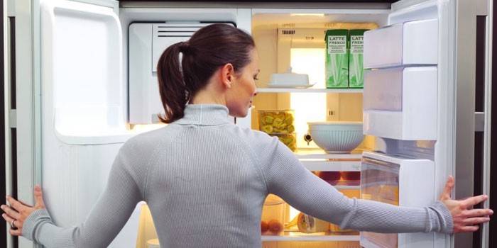 Девушка перед открытым холодильником