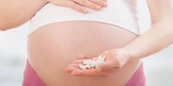 Беременная девушка с таблетками в руке