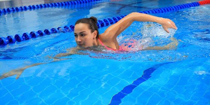 Девушка плавает в бассейне