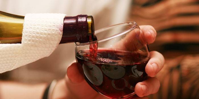 Красное вино наливают из бутылки в бокал