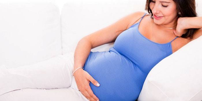 Беременная девушка лежит на диване