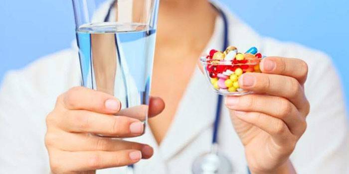Таблетки и стакан воды в руках у медика