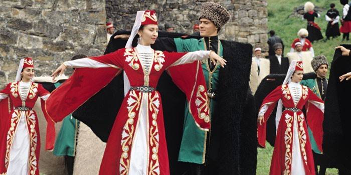 Женщины и мужчины в чеченских костюмах танцуют