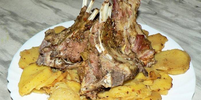 Блюдо с запеченными бараньими ребрами на подушке из картофеля