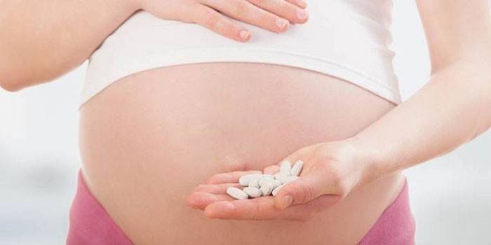 Беременная женщина с таблетками в ладони