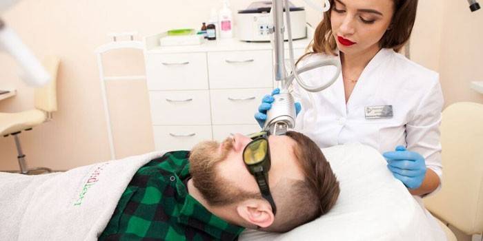 Медик проводит лазерное удаление невуса у мужчины на лице