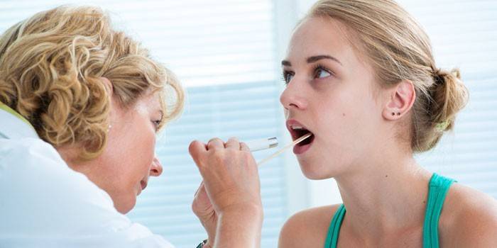 Оториноларинголог осматривает горло пациентки