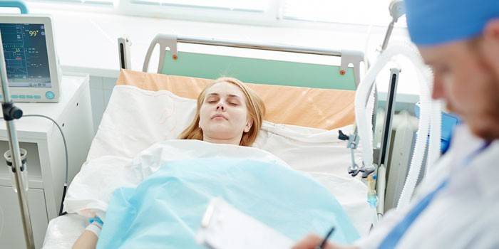 Девушка лежит в больничной палате и врач записывает показания приборов
