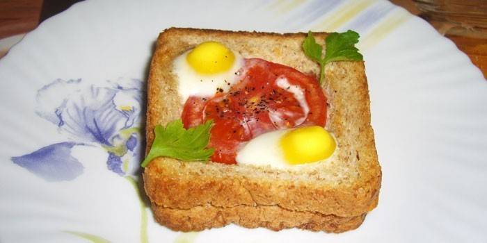 Горячий бутерброд с перепелиными яйцами и помидором на тарелке