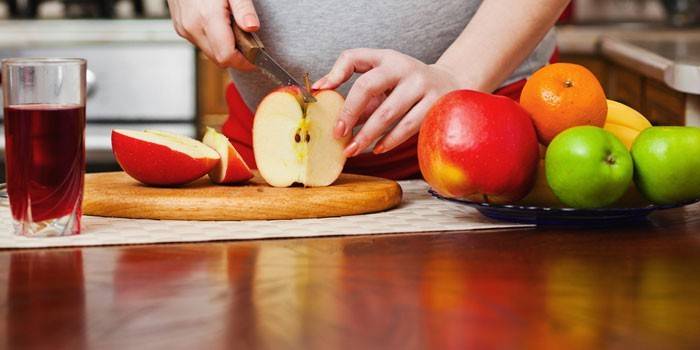 Беременная девушка режет яблоко