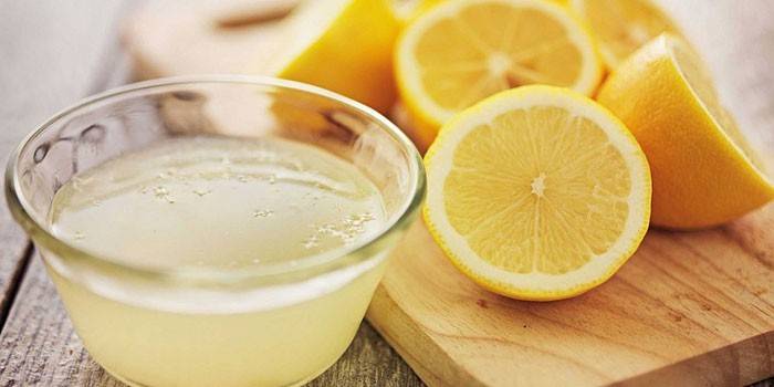 Сок лимона в тарелочке и половинки лимонов