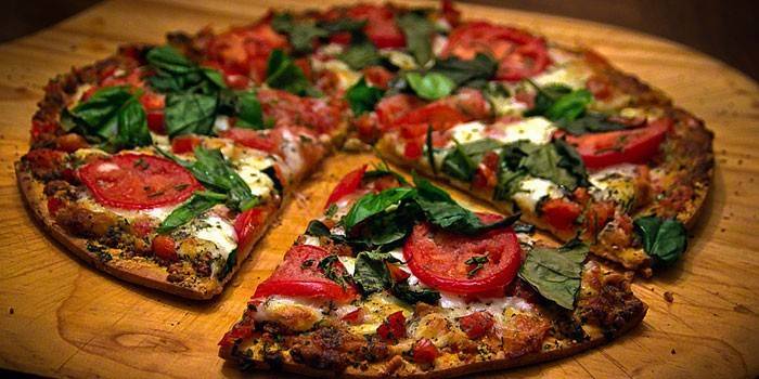 Пицца на тонком корже с начинкой из помидоров и моцареллы с базиликом