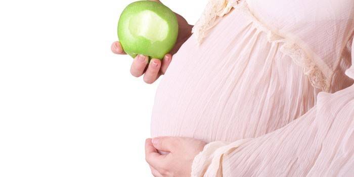 Беременная женщина с яблоком в руке