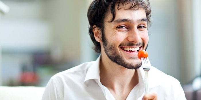 Мужчина кушает помидор черри