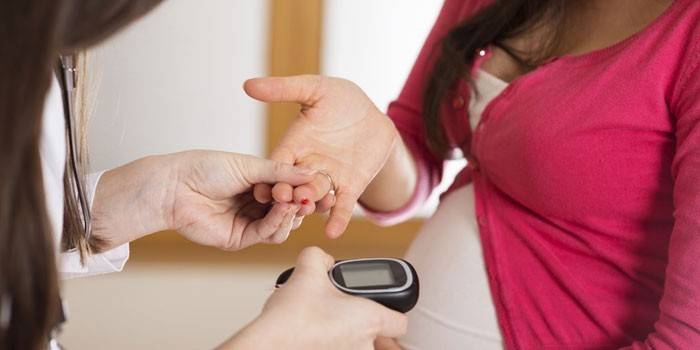 Беременной девушке измеряют уровень сахара в крови глюкометром